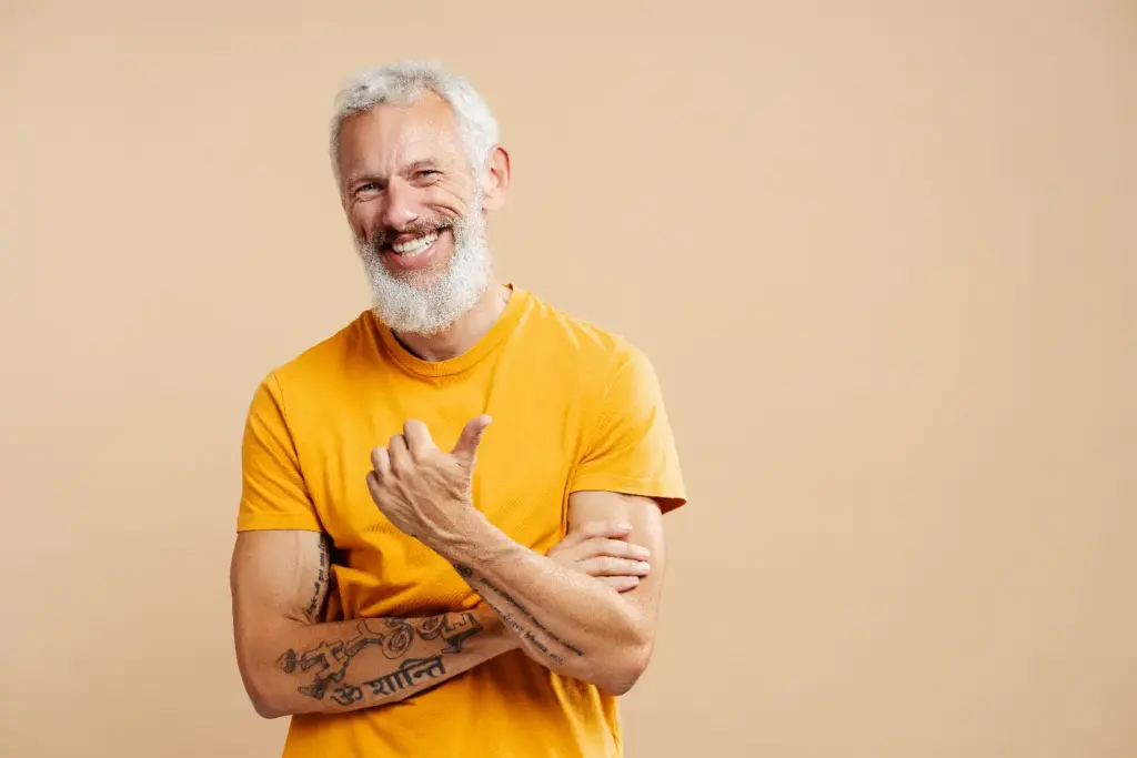 Older gentleman with bird in yellow short sleeve shirt, showing tattoos
